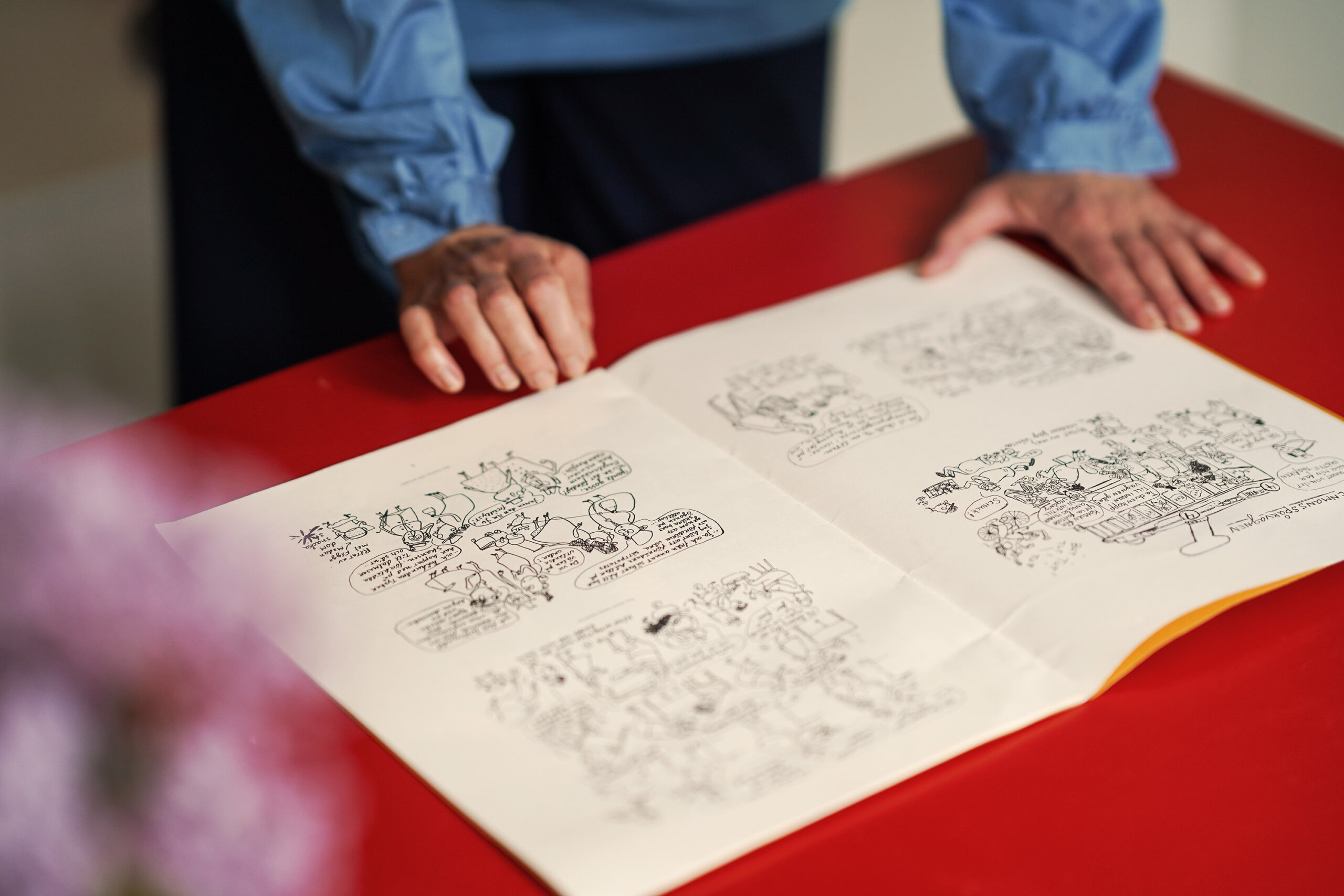 Maja Sten visar gammal tidning med illustrationer som hennes farfar gjort