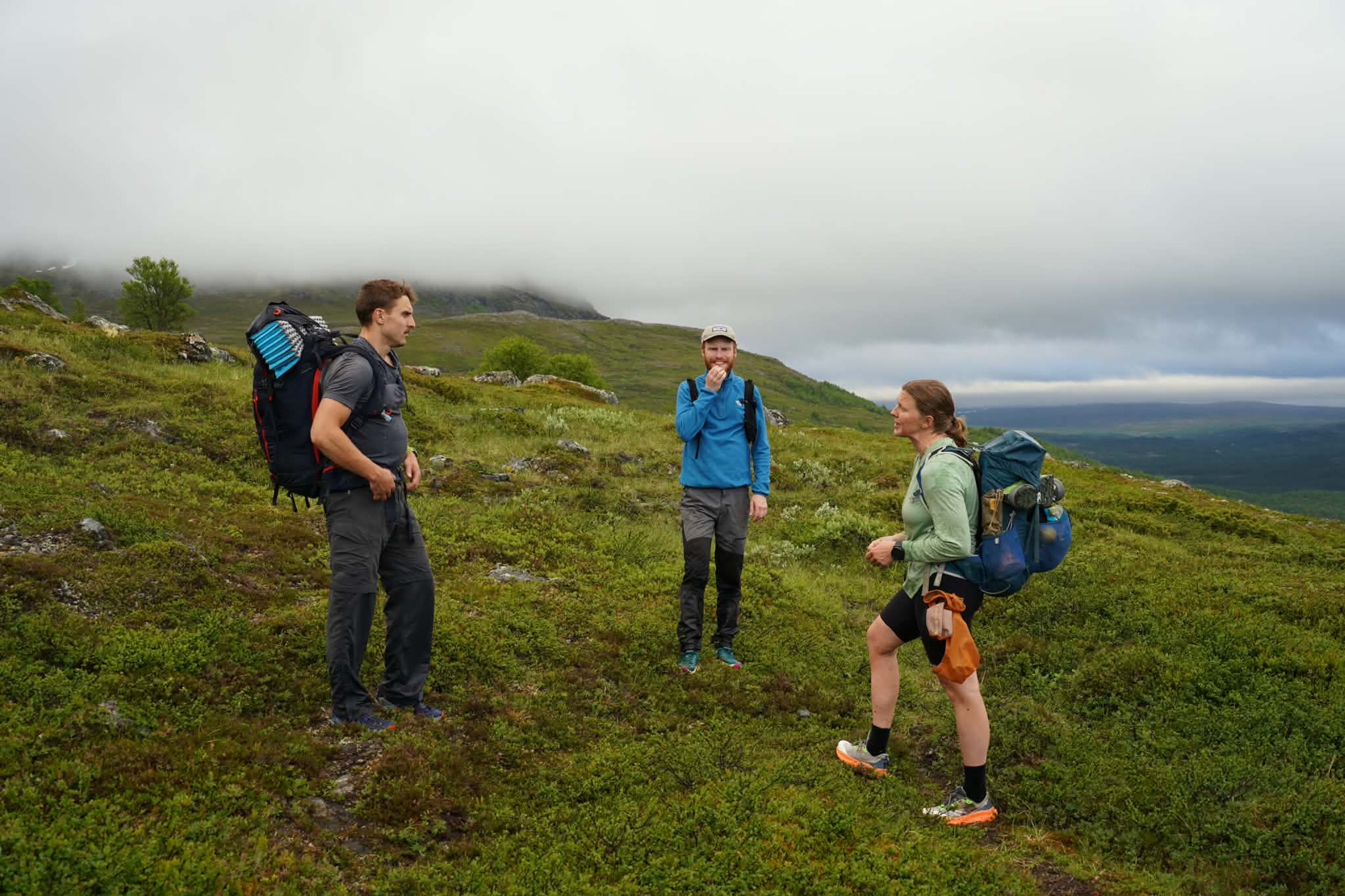 Tre fjällguider står på ett berg och pratar