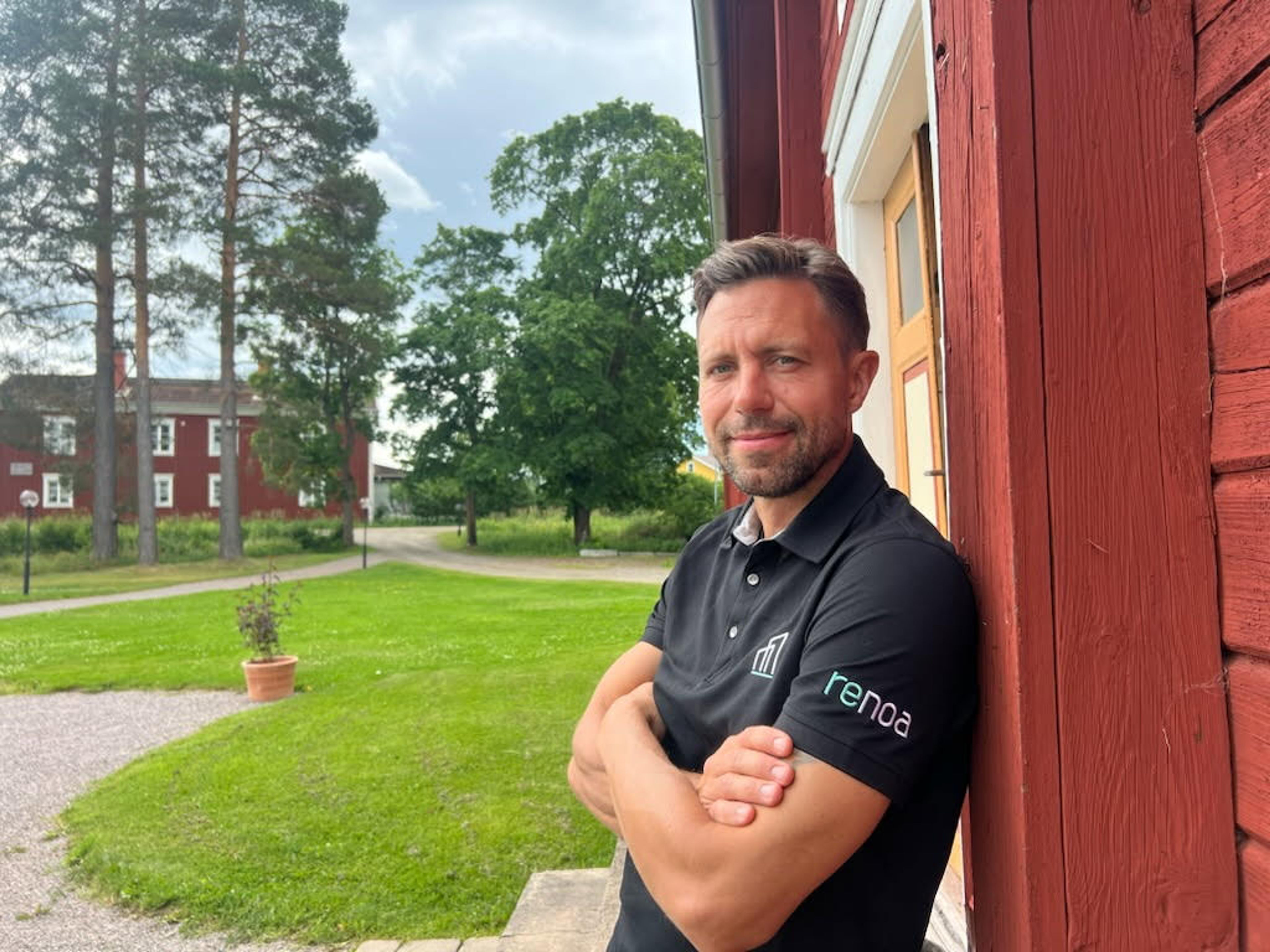 Man lutar sig mot en husvägg och tittar in i kameran
